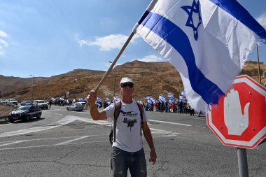 Ölü Deniz sahilinde şemsiyeli kırmızı elbiseli iki kadın.