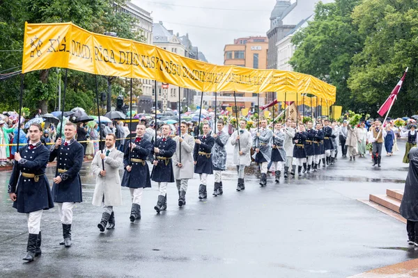 ラトビア 2023年7月2日 ラトビア全国歌舞祭オープニングパレードの参加者は民謡の言葉で長い黄色のバナーを運ぶリガリサウンズリガ ディムド — ストック写真