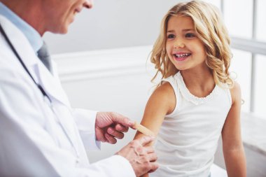 Bir çocuk doktoru mahkeme sıva kolunu doktor ofisinde otururken üzerinde yapışmasını ise sevimli küçük kız gülümsüyor