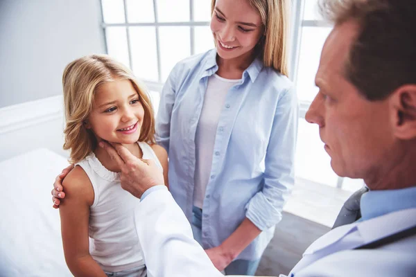 英俊的中间岁儿科医生正在小女孩脉率 可爱的小女孩和她美丽的母亲笑着 坐在医生办公室 — 图库照片