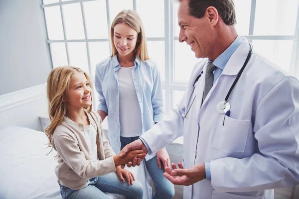 小女孩和她美丽的母亲 在儿科医生咨询 女孩是微笑和英俊的中间岁医生的握手 — 图库照片