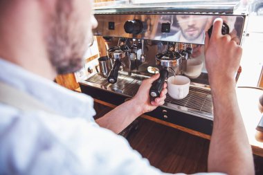Yakışıklı genç barista kahve kentsel kafede bir modern kahve makinesi kullanarak görüntü kırpılmış