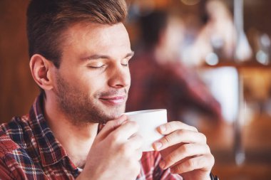 Bir fincan tutarak ve modern bir kent kafede otururken kahve zevk yakışıklı genç adam portresi