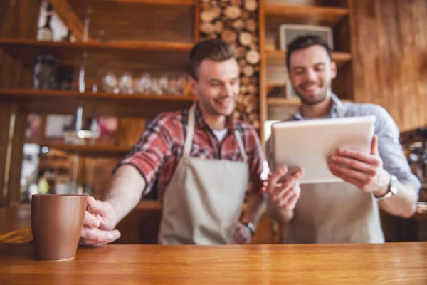 Dos Jóvenes Trabajadores Cafetería Guapos Están Usando Una Tableta Sonriendo — Foto de Stock