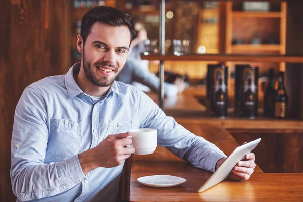 Bonito Jovem Empresário Está Usando Tablet Bebendo Café Olhando Para — Fotografia de Stock