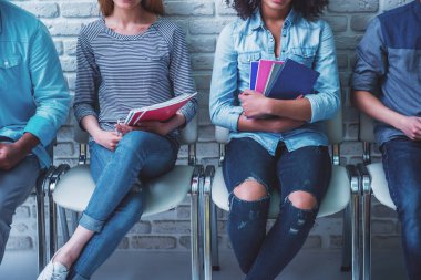 Farklı milletlerden sınav için beklerken kitap ve defter tutan gençlerin kırpılmış görüntü