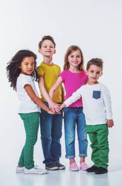 Rahat giysiler içinde sevimli küçük çocukların tam uzunlukta portre birlikte el ele, kamera bakarak ve gülümseyerek, beyaz bir arka plan üzerinde izole