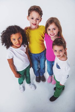 Kameraya bakan ve gülümseyen, beyaz bir arka plan üzerinde izole sevimli küçük çocukların yüksek açılı görünümü