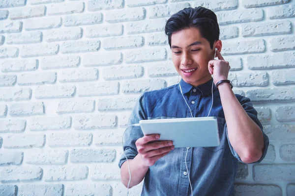 Bonito Cara Asiático Está Ouvindo Música Usando Tablet Sorrindo Enquanto — Fotografia de Stock