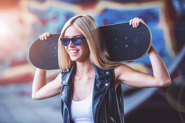 Krásná Blonďatá Dívka Brýlích Drží Její Skateboard Hlavu Úsměvem Stoje — Stock fotografie