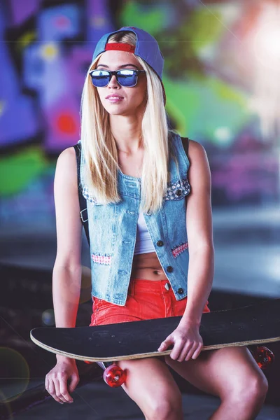 Красивая Блондинка Кепке Очках Смотрит Сторону Сидя Своим Скейтбордом Скейт — стоковое фото