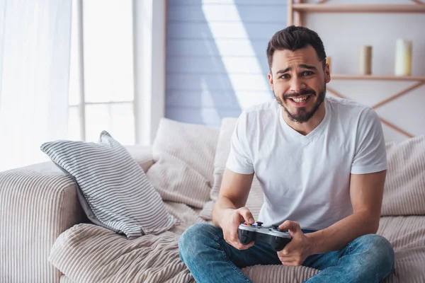 Knappe Man Spelen Game Console Het Maken Van Gezichten Zittend — Stockfoto