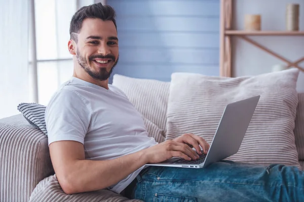 Hombre Guapo Está Usando Ordenador Portátil Mirando Cámara Sonriendo Mientras —  Fotos de Stock