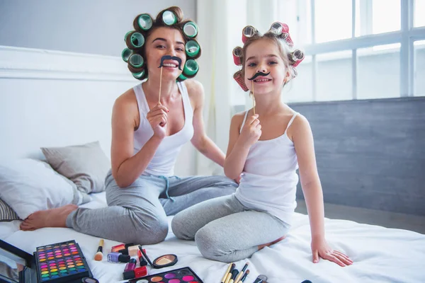 어머니와 그녀의 귀여운 머리카락 Curlers 스틱에 집에서 침대에 앉아있는 — 스톡 사진