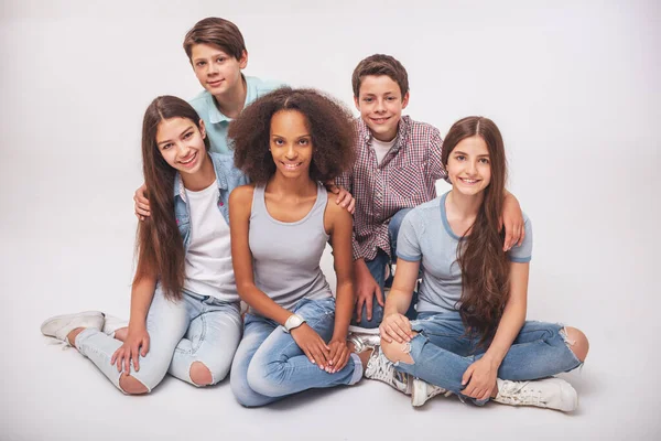 集团的十几岁的男孩和女孩看着相机和坐 微笑着上白色孤立 — 图库照片