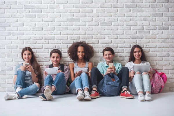 Grupa Nastoletnich Chłopców Dziewcząt Jest Korzystanie Gadżetów Patrząc Kamery Uśmiechnięty — Zdjęcie stockowe
