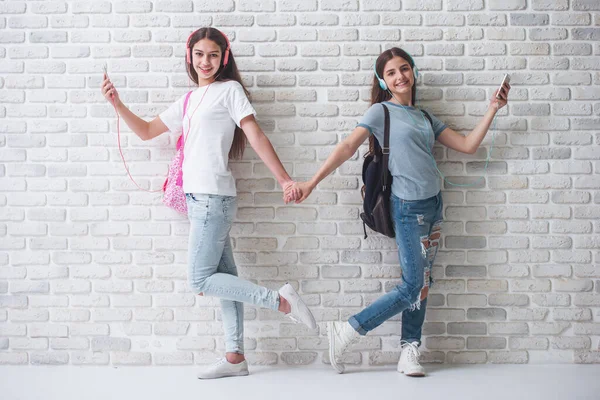 Dwie Nastoletnie Dziewczyny Słuchawkach Słuchania Muzyki Pomocą Smartfonów Trzymając Się — Zdjęcie stockowe