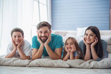 Güzel genç anne, onların sevimli küçük kızı ve oğlu kamera bakıyor ve gülümseyerek, evde yerde yatıyor