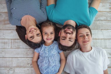 Güzel anne, onların şirin küçük kızı ve kameraya bakıyor ve gülümsüyor, ahşap yerde yatarken oğlu üstten görünüm
