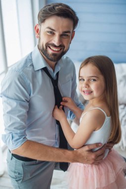 Sevimli küçük kızını babasının kravat ayarlıyor. Her ikisi de kameraya bakıyor ve gülümsüyor