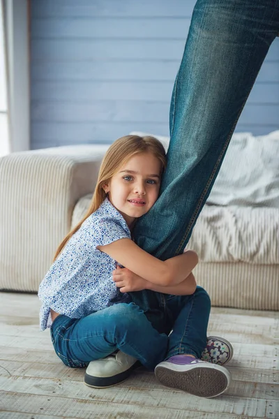 裁剪图像的可爱的小女孩看着相机 微笑着拥抱她父亲的腿不让他走 — 图库照片