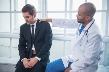 Yakışıklı Afro Amerikalı doktor işadamı'nın omuzlarında onu yatıştırıcı süre el tutuyor