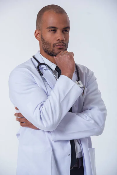 肖像的英俊沉思的非裔美国医生白大衣手还盯着他的下巴 看着别处和思考 在白色背景上孤立 — 图库照片
