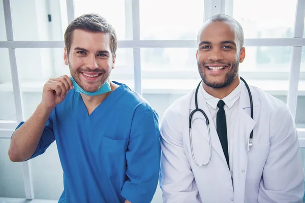 Dwóch Lekarzy Przystojny Patrząc Kamery Uśmiechnięty Siedzi Szpitalu — Zdjęcie stockowe