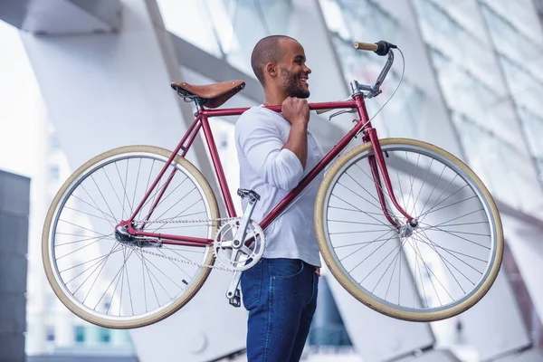 アウトドアで自転車を持ちながら笑顔でカジュアルな服を着たハンサムな若いビジネスマンの側面図 — ストック写真