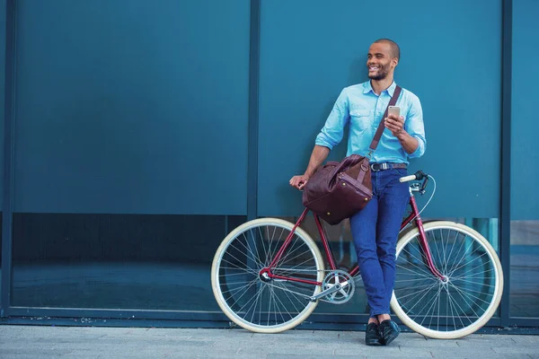 携帯電話を使用してカジュアルな服のハンサムな若いビジネスマンの完全な長さの肖像画 離れて見て 彼の自転車にもたれながら笑顔 屋外に立って — ストック写真
