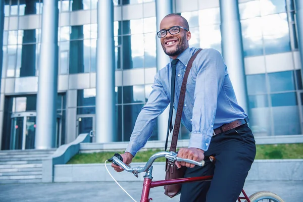 古典的な服や眼鏡でハンサムなビジネスマンはオフィスビルの外で彼の自転車に乗っている間笑っている — ストック写真