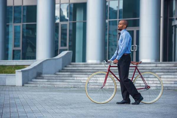 穿着经典服装 骑着自行车在办公楼外散步的英俊商人的侧影 — 图库照片