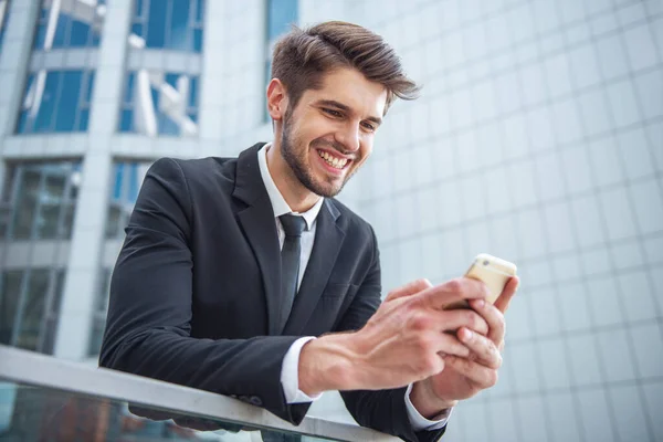 Bonito Jovem Empresário Terno Clássico Está Usando Smartphone Sorrindo Fora — Fotografia de Stock