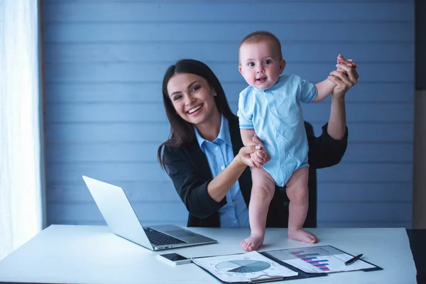 美丽的商务女士在经典西装和她的可爱的小宝宝手牵手 看着相机和微笑 而在办公室工作 — 图库照片