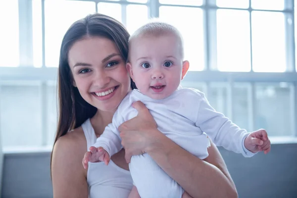 Portrait of beautiful young mom and her sweet little baby looking at camera and smiling