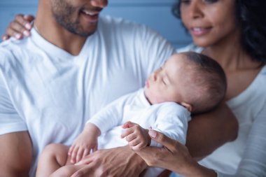 Küçük bebek baba kollarında uyurken gülümseyen güzel genç Afro Amerikalı ebeveynlerin Kırpılmış görüntü