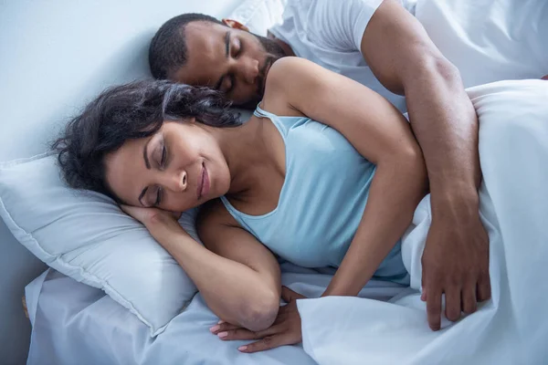Beautiful young Afro American couple is sleeping in their bed at home