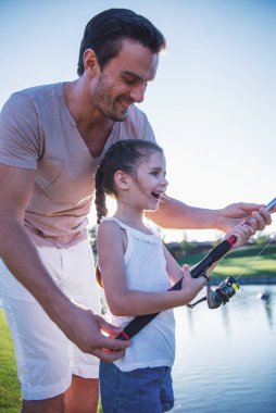 Yakışıklı baba ve güzel küçük kızı kullanarak bir olta balık yakalamak gülüyorsun