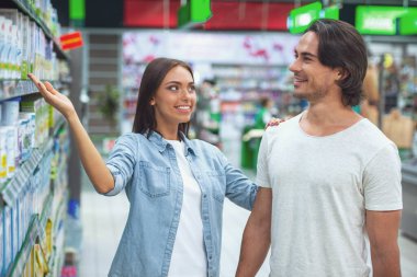 Güzel genç çift konuşmak ve süpermarket gıda seçerken gülümseyen