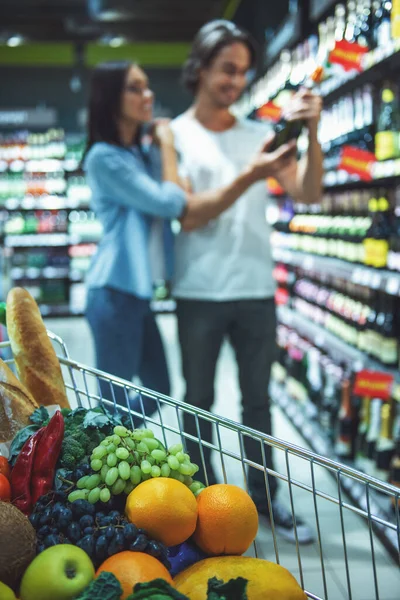 Корзина Едой Заднем Плане Красивая Молодая Пара Выбирает Напиток Супермаркете — стоковое фото