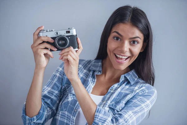 穿着休闲装的漂亮少女拿着相机 看着相机 面带微笑 在灰色背景 — 图库照片