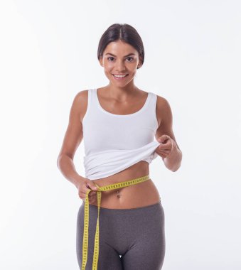 Spor giyim güzel genç sporcumuz beline bir mezura kullanarak, bir kamera seyir ölçme ve gülümseyen, üzerinde beyaz izole