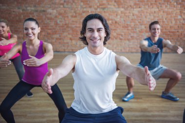 Güzel spor insanlar egzersizleri yapıyor ve modern bir fitness salonunda antrenör ile dışarı çalışırken gülümseyen