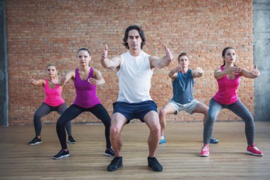 Güzel spor insanlar modern fitness salonunda antrenör ile dışarı çalışırken egzersizleri yapıyor