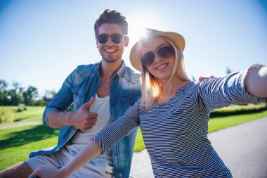 Güzel çift selfie yapma ve parkta Bisiklete binme süre gülümseyen