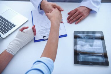 Onun ofisinde çalışırken Bayan hasta elini sıkarken yakışıklı tıp doktoru kırpılmış görüntü