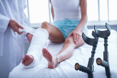 Yakışıklı doktor ofisinde çalışırken kadının kırık bacak sarmak kırpılmış görüntü