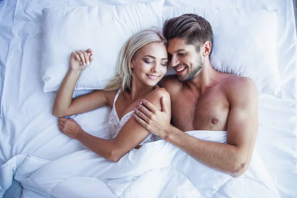 顶视图的性感的年轻夫妇 拥抱和微笑着一起睡在床上 — 图库照片