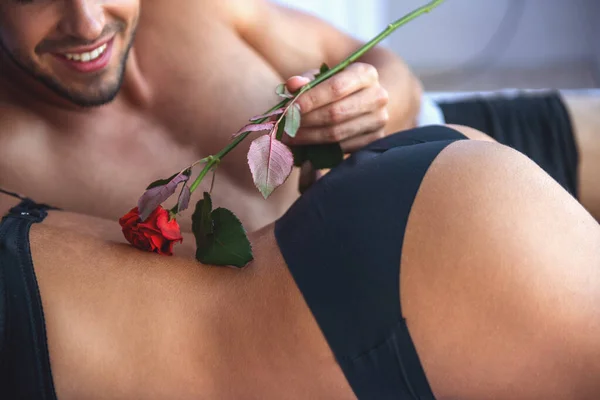 裁剪图像的美丽充满激情的夫妇在床上做爱 男人触摸他的伙伴带一朵玫瑰 — 图库照片