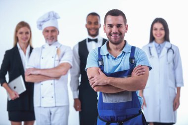 Üniformalı farklı meslek güzel insanlar kameraya bakıyor ve gülümsüyor, üzerinde beyaz izole. Yakışıklı işçi planda